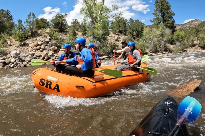 a group of people riding on the back of a boat in the water