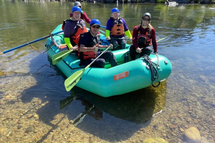 Four people in helmets and vests rafting on a river.