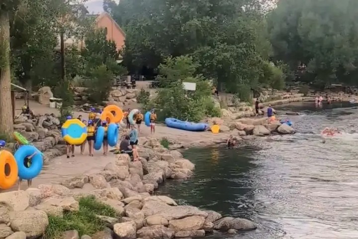 People with tubes near rocky riverbank preparing to float.
